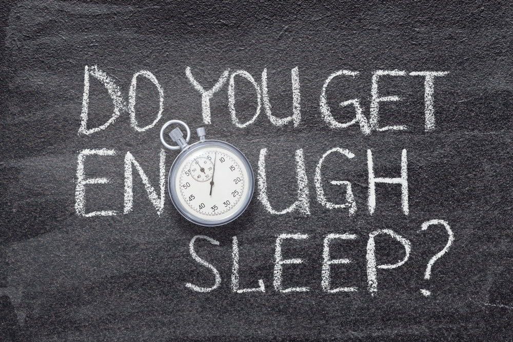 The words Do you get enough sleep? Written on a chalk board with an alarm clock
