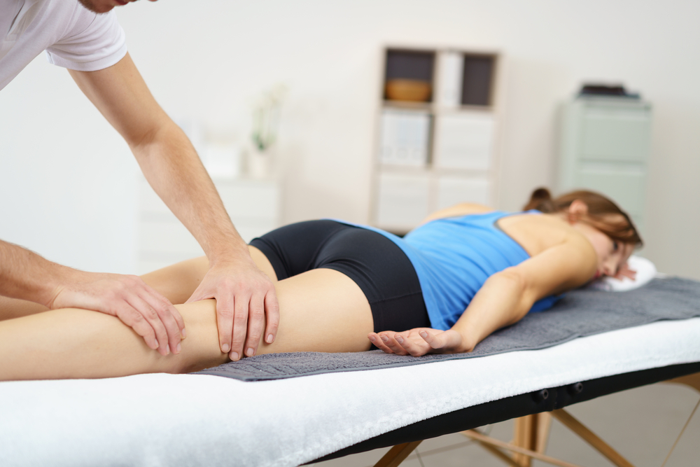 Woman receiving sports massage to leg to relieve joint pain