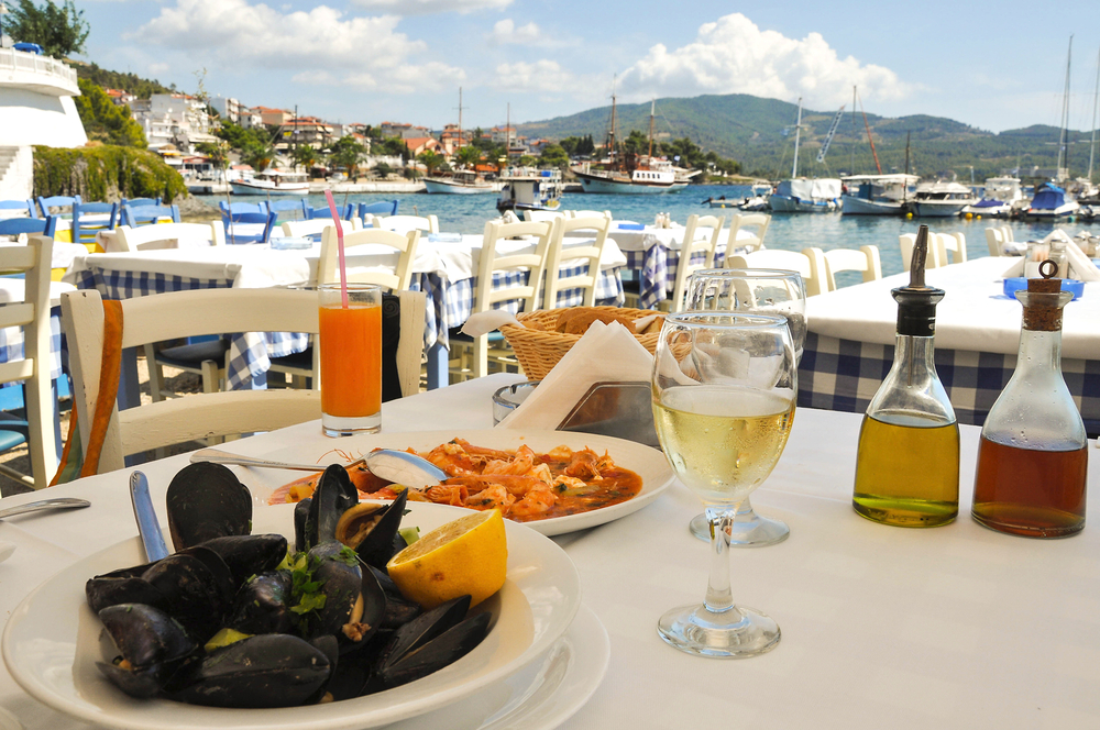 A meal of seafood on a table overlooking a harbour in Greece