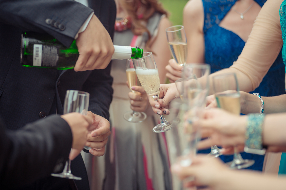 A close up of people at a party toasting with champagne