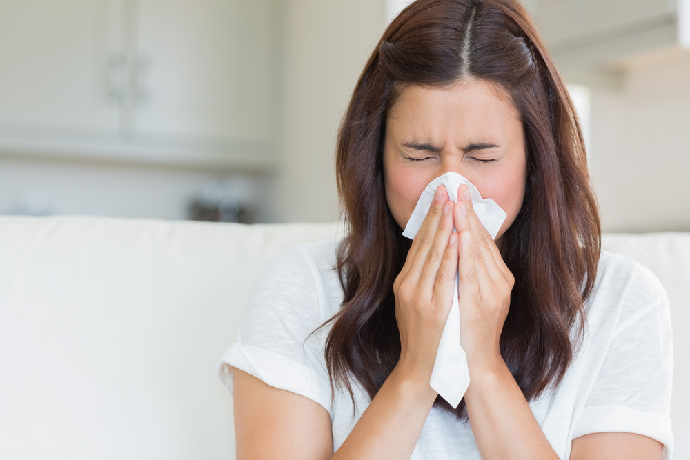 Close up of woman blowing her nose to represent cold and flu