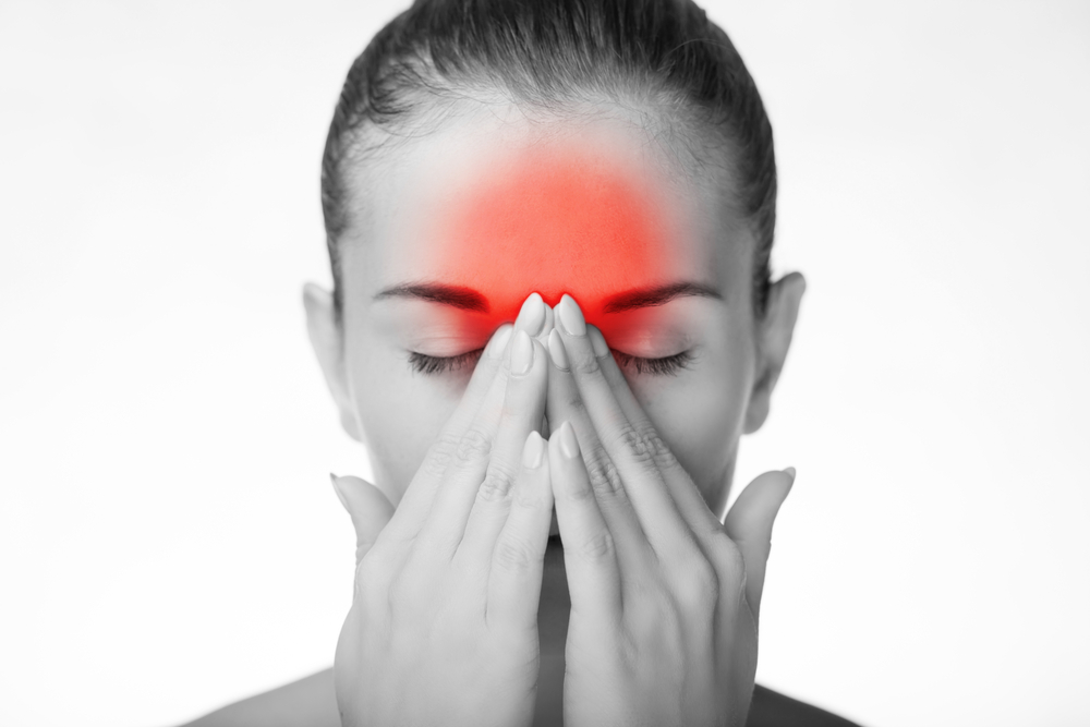Black and white image of woman with red glow on forehead to represent migraine