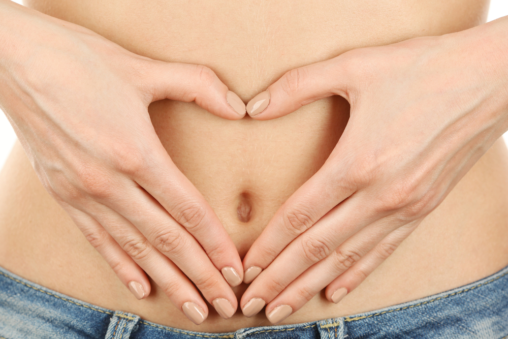 Close up of woman's tummy with hands making a heart shape to represent digestion