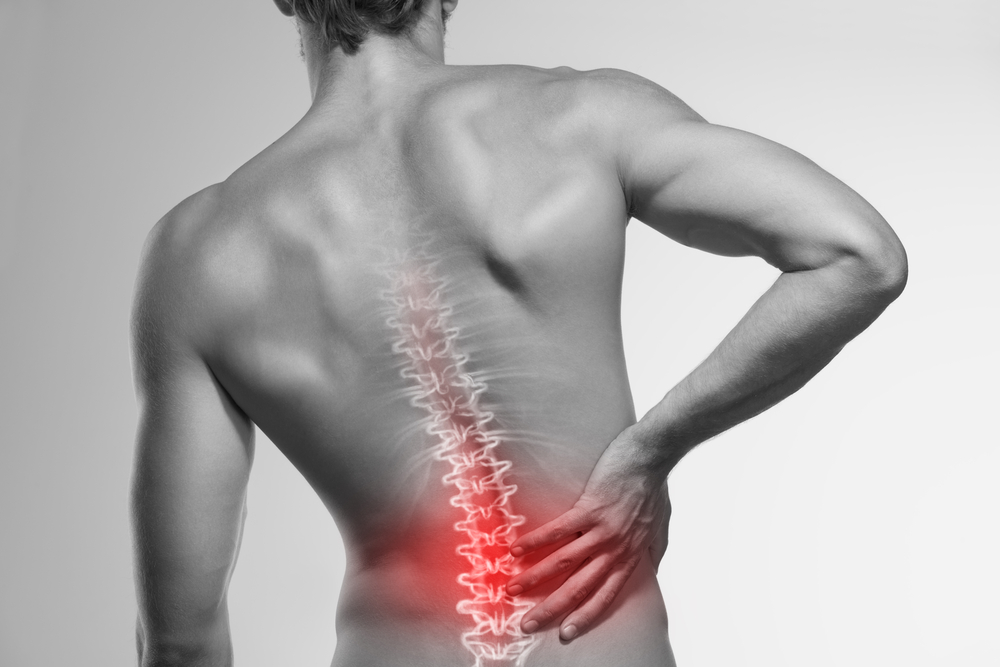Bl;ack and white image of man's back with the lower spine glowing red to represent pain