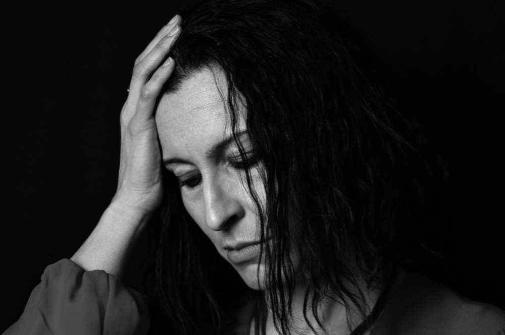 BLack and white close up of woman with head in hands to represent low mood and stress