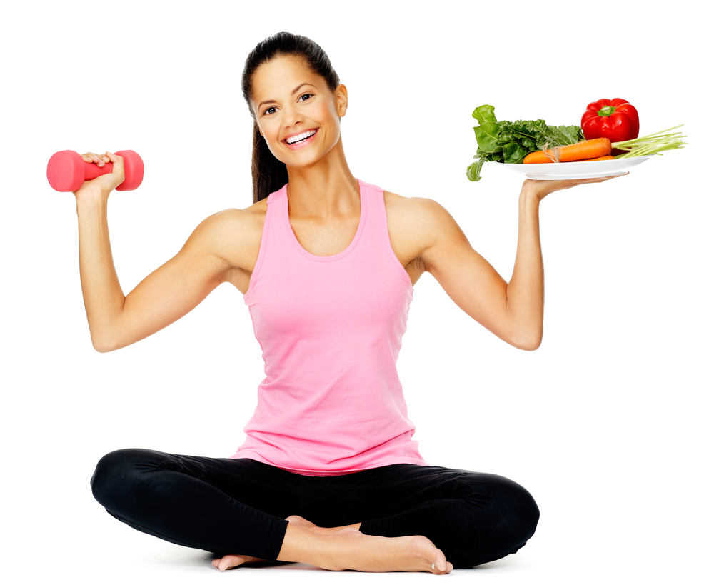 Woman holding a plate of fruit and veg in one hand and a weight in the other