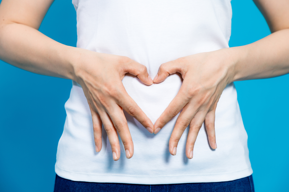 Close up of woman making a heart shape with her hands over her tummy to represent good digestion